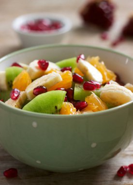 Dilim bir ahşap zemin üzerine nar taneleri ve çeşitli meyve salatası.