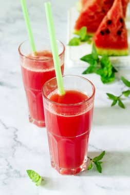 Bir cam bardak ve dilim karpuz hafif bir arka plan üzerine nane ile soğuk karpuz limonata.