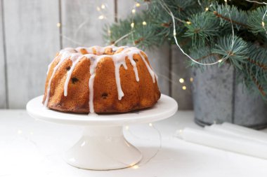 Kuru üzüm ve köknar şube ve çelenk zemin üzerine pudra şekeri krema ile pasta. Rustik tarzı, seçici odak.