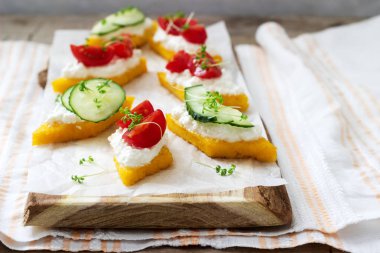 Vejetaryen kanepeler polenta ile peynir, sebze ve tere hafif bir arka plan üzerinde üzerinden. Rustik tarzı.