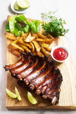 Ev yapımı pişmiş et kaburga patates kızartması, otlar, limon ve bir ahşap tahta ketçap ile devam eder. Rustik tarzı.