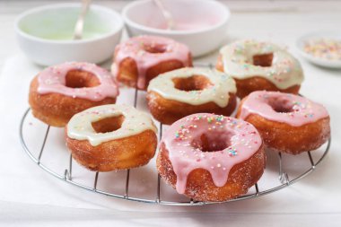 Ev yapımı çörek renkli buzlanma ve hafif bir arka plan üzerinde renkli şeker ile dekore edilmiştir. Seçici odak.