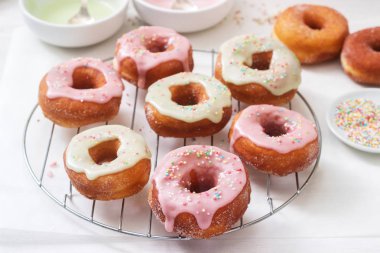 Ev yapımı çörek renkli buzlanma ve hafif bir arka plan üzerinde renkli şeker ile dekore edilmiştir. Seçici odak.