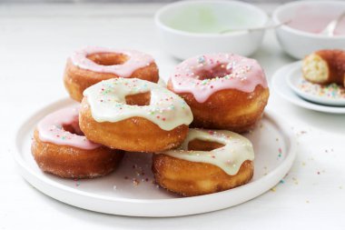 Ev yapımı çörek renkli buzlanma ve hafif bir arka plan üzerinde renkli şeker ile dekore edilmiştir. Seçici odak.