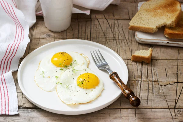 stock image Breakfast of fried eggs, bread toasts and coffee on a wooden table. Rustic style, selective focus.