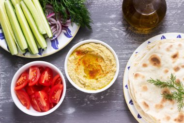 Vegan yemek, gözleme, sebze ve beton zemin üzerine zeytin yağı ile ev yapımı humus. Seçici odak.
