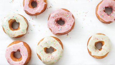 Ev yapımı çörek renkli buzlanma ve hafif bir arka plan üzerinde renkli şeker ile dekore edilmiştir. Seçici odak.