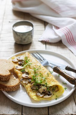 Vejetaryen Kahvaltı, omlet mantar ve tere, çavdar ekmeği ve sütlü kahve ile devam eder. Rustik tarzı, seçici odak.