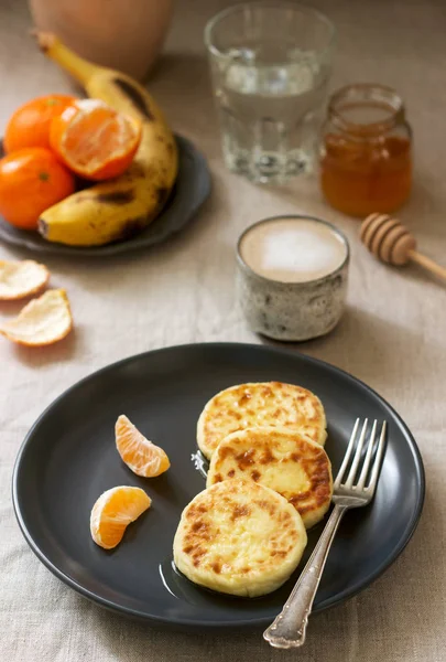 Vegetarian breakfast of quark pancakes with honey, fruit and coffee with milk. Rustic style. — Stock Photo, Image