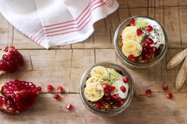 Granola yoğurt ve meyve ahşap bir masa üzerinde kavanozların içinde. Rustik tarzı, seçici odak.