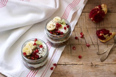 Granola yoğurt ve meyve ahşap bir masa üzerinde kavanozların içinde. Rustik tarzı, seçici odak.