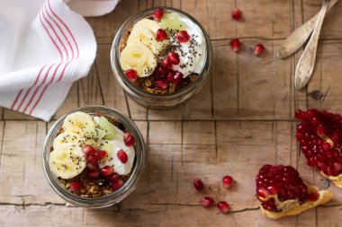 Granola yoğurt ve meyve ahşap bir masa üzerinde kavanozların içinde. Rustik tarzı, seçici odak.