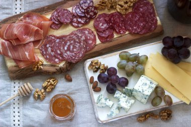 Çeşitli sosisler, jambon, peynir, fındık ve üzümlerden şaraplar. Kırsal biçim, seçici odak.