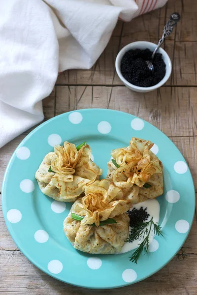 Bolsas de panqueques rellenos de arenque, servidos con caviar, crema agria y eneldo sobre un fondo de madera. Estilo rústico . —  Fotos de Stock