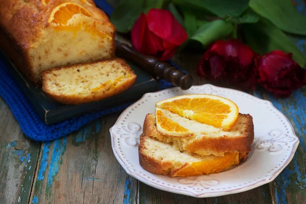 Помаранчевий торт, прикрашений скибочками апельсина на тлі соковитих апельсинів і букетом тюльпанів. русичний стиль . — стокове фото