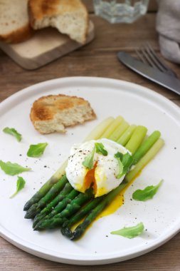 Ahşap bir yüzeyde tereyağı ve marul ile haşlanmış yumurtalı ve pişmiş kuşkonmamış kahvaltı. Rustik tarzı.
