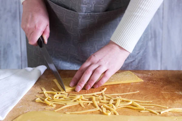 Una mujer hace fideos caseros con harina, huevos y sal. Estilo rústico . — Foto de Stock