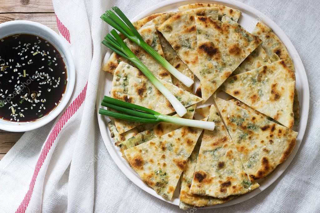Homemade appetizing scallion pancakes and a bunch of green onions. Rustic style.