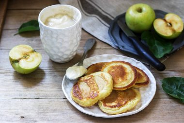 Ahşap bir arka planda ekşi krem, kahve ve yeşil elma ile ev yapımı elma börek. Rustik tarzı.