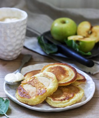 Ahşap bir arka planda ekşi krem, kahve ve yeşil elma ile ev yapımı elma börek. Rustik tarzı.