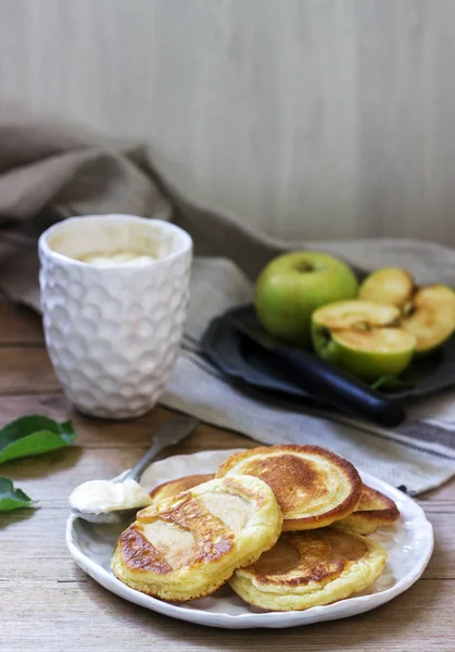 Buñuelos de manzana caseros con crema agria, café y manzanas verdes sobre un fondo de madera. Estilo rústico . — Foto de Stock