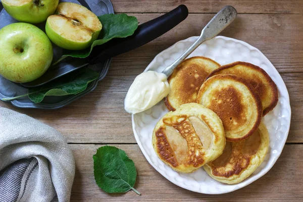 Buñuelos de manzana caseros con crema agria, café y manzanas verdes sobre un fondo de madera. Estilo rústico . — Foto de Stock