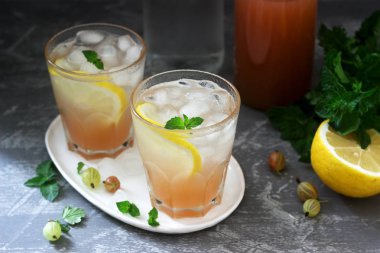 Nane ve buz ile bektaşi üzümü limonata, bir şişe su ve beton bir yüzey üzerinde bektaşi üzümü şurubu bir şişe.