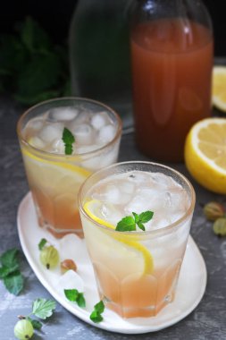 Nane ve buz ile bektaşi üzümü limonata, bir şişe su ve beton bir yüzey üzerinde bektaşi üzümü şurubu bir şişe.