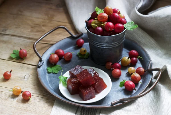 Cubes de confiture de groseilles à maquereau et groseilles à maquereau sur un plateau. Style rustique . — Photo