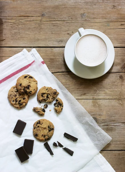 Шоколадное печенье, кусочки шоколада и чашка какао или кофе с молоком на деревянном фоне. Сельский стиль . — стоковое фото