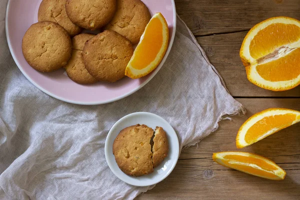 Crispy cookies with candied orange and sliced orange on a wooden surface. Rustic style.