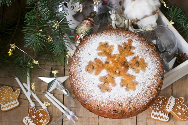 Traditional Christmas fruitcake on the background of a box with Christmas toys and fir branches. — Stock Photo, Image