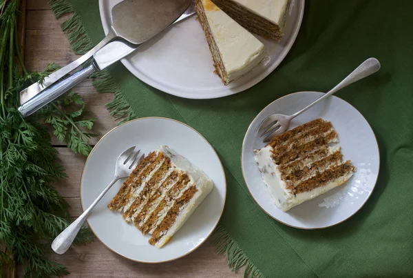 Carrot cake, pieces of cake with curd cream and carrots on a wooden background. Rustic style.