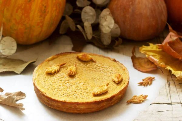 Torta casera tradicional de calabaza americana, decorada con galletas sobre un fondo de calabazas y hojas de otoño . — Foto de Stock