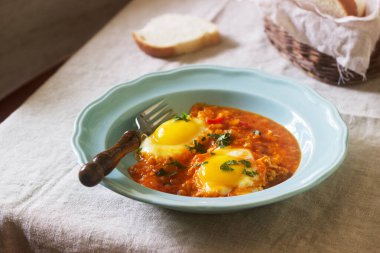 Ahşap bir masa üzerinde ekmek ile Shakshuka. Orta Doğu geleneksel çanak. Ev yapımı. Seçici odak.