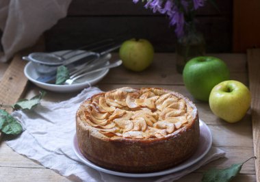 Elma kremalı turta, ahşap arka planda elmalar ve tabaklar. Kırsal biçim, seçici odak.