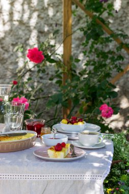Güveçten, böğürtlenden, sostan ve içecekten bahçede kahvaltı. Kırsal biçim, seçici odak.