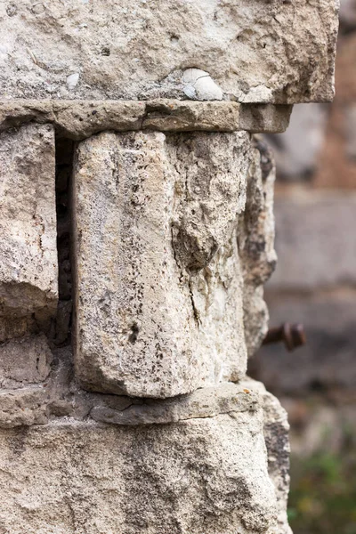 An old crumbling wall of cauldron and cement, illuminated by the sun. Selective focus.