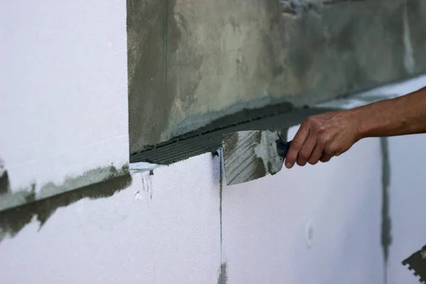 Wall insulation with polystyrene panels, glue application and installation. Selective focus.
