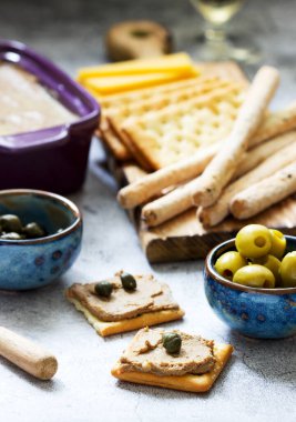 Tavuk ciğeri, soğan ve havuç ezmesi, yanında kraker, Grissini, zeytin, kapari ve şampanya. Seçici odak.