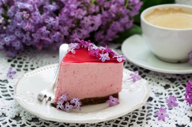 Çikolata bazlı ve meyve suyu jöleli, leylak çiçekleriyle süslenmiş, kahveyle servis edilen dutlu kek. Seçici odak.