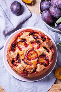 Doldurulmuş erik turtası ve şeker hamuru. Tahta bir masanın üzerine pudra şekeri ve erik serpiştirilmiş. Sonbahar durgun hayat, köy tarzı, seçici odaklanma.