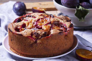 Doldurulmuş erik turtası ve şeker hamuru. Tahta bir masanın üzerine pudra şekeri ve erik serpiştirilmiş. Sonbahar durgun hayat, köy tarzı, seçici odaklanma.