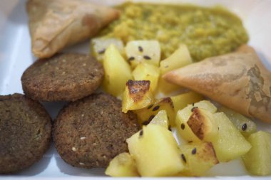 Falafel, kavrulmuş patates, samosa ve daal ile çeşitli vegan plaka