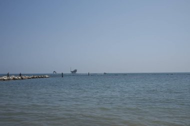 Lido di Dante, 06 Ağustos 2019 : Lido di Dante taş iskele ve arka planda Adriyatik denizinde petrol ve doğal gaz çıkarma platformlarının görünümü