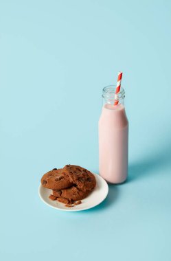 uçan daire ve çilek milkshake içme saman üzerinde mavi arka plan ile şişe içinde çikolata kurabiye 