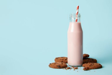 çikolata kurabiye ve milkshake içme saman üzerinde mavi arka plan ile şişe 