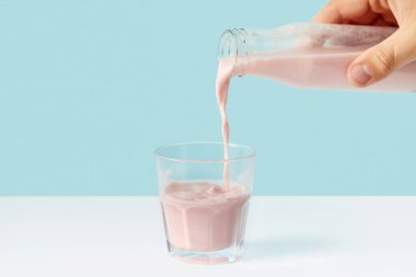 adam dökme çilekli milkshake bardak cam şişe mavi zemin üzerine içine kesilmiş 