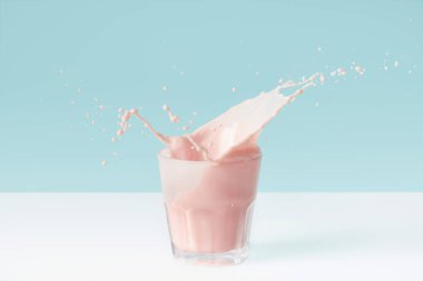 Çilekli milkshake cam mavi zemin üzerine damla sıçramasına 