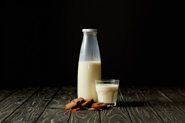 chocolate cookies, milk in bottle and glass on black background 